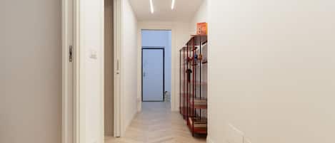 A hallway with a wooden floor, white walls, and a door at the end.