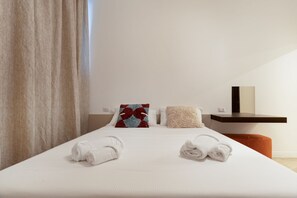 A neatly made bed with white linens and two towels, a red and blue patterned pillow, and a beige throw pillow. - A comfortable 73 sqm apartment, ideal for 6 people, located on the lower ground floor of a building with an elevator.The apartment enjoys a strategic location, just 450 meters from the “Porta Romana” stop on the M3 (Yellow) metro line, which takes yo (Milan)