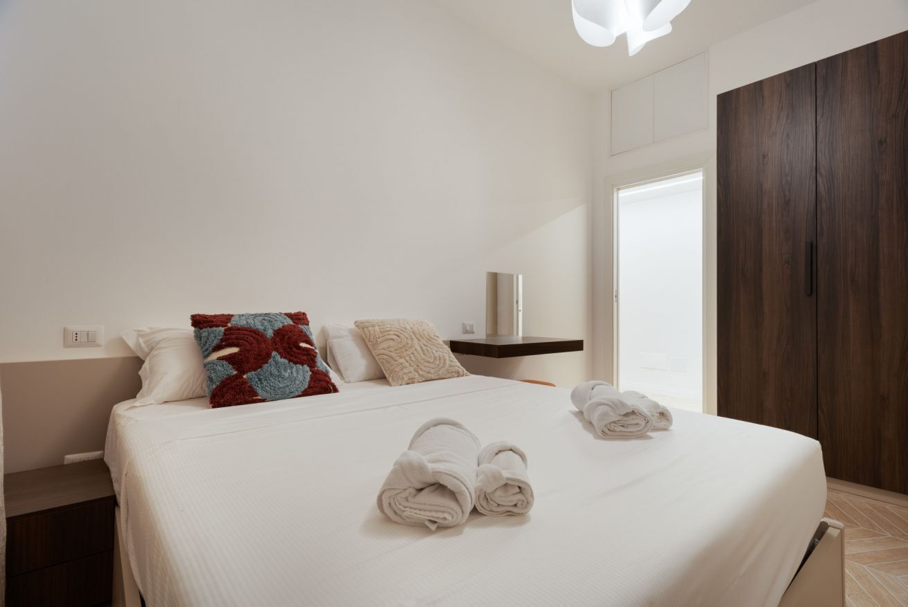 A hotel room with a large bed, a bedside table, a wardrobe, and a window.