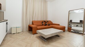 Una sala de estar moderna con sofá, una mesa de centro, una zona de cocina y un espejo grande.