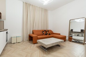 Ein modernes Wohnzimmer mit Sofa, Couchtisch, Küchenbereich und einem großen Spiegel.