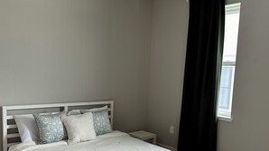A bedroom with a bed, bedside tables, a window with curtains, and a ceiling light. - Modern South Philly Townhome. Rooftop. Skyline Views. Home Office.  Gym (Philadelphia)