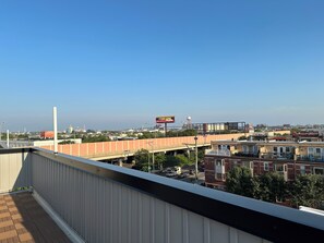 Blick vom Balkon auf eine Stadtansicht mit einer Brücke, Gebäuden und blauem Himmel.