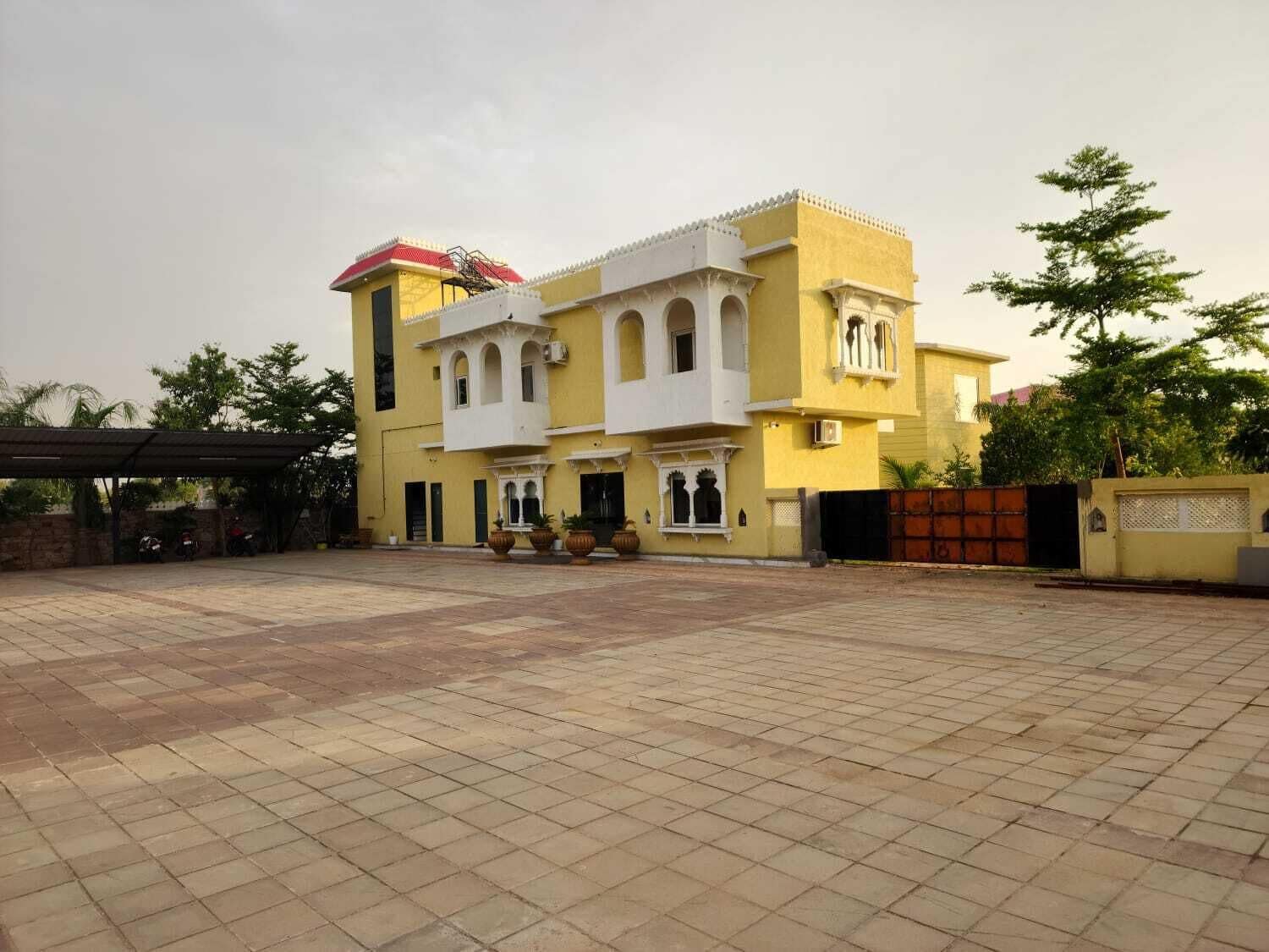 A two-story building with a tiled courtyard, a red roof, and a gated entrance.
