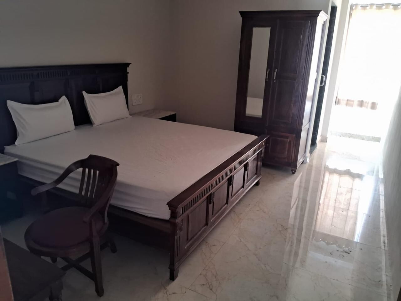 Un dormitorio con cama, armario de madera y una silla.