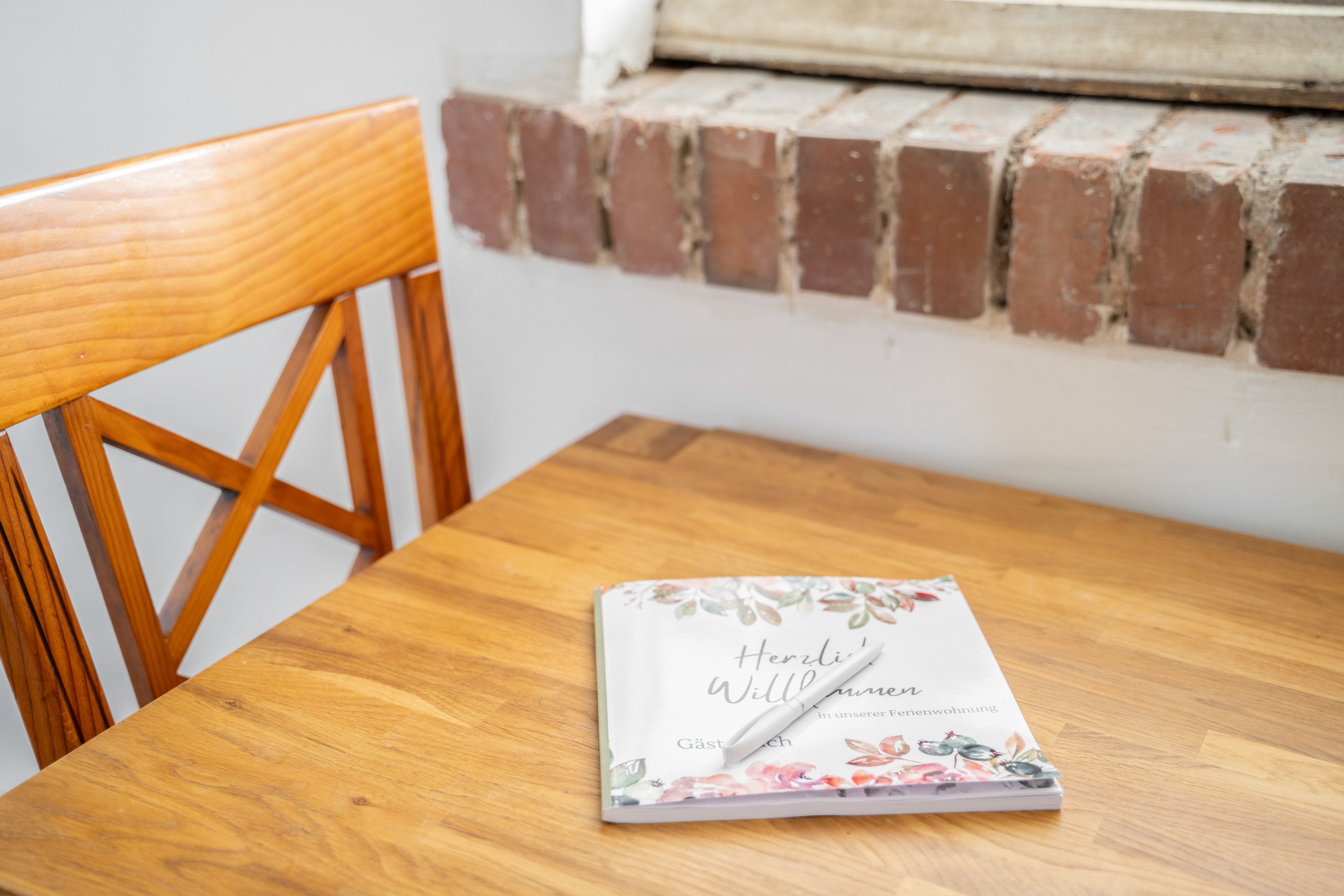 A wooden table with a book titled 'Herli Williuren' and a pen on it.