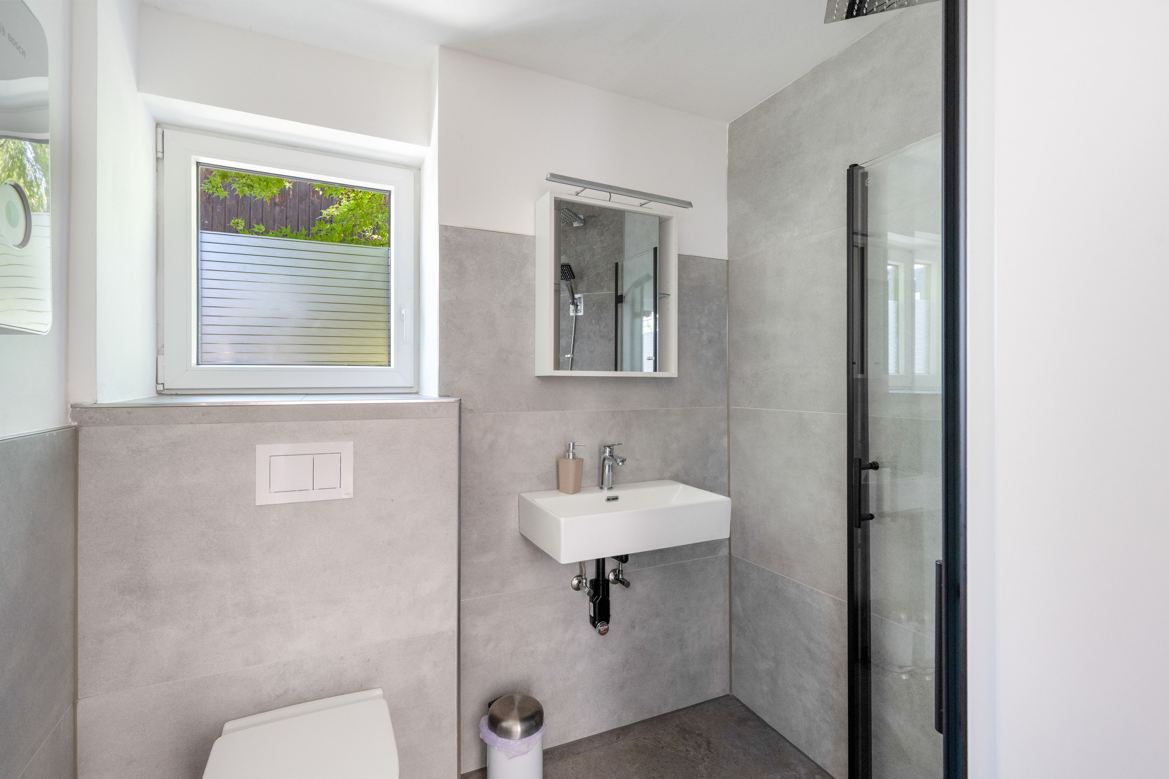Ein modernes Badezimmer mit Dusche, Waschbecken und Fenster.