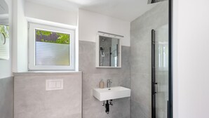 Une salle de bain moderne avec une douche, un lavabo et une fenêtre.