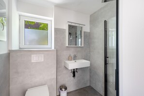 A modern bathroom with a shower, a sink, and a window.