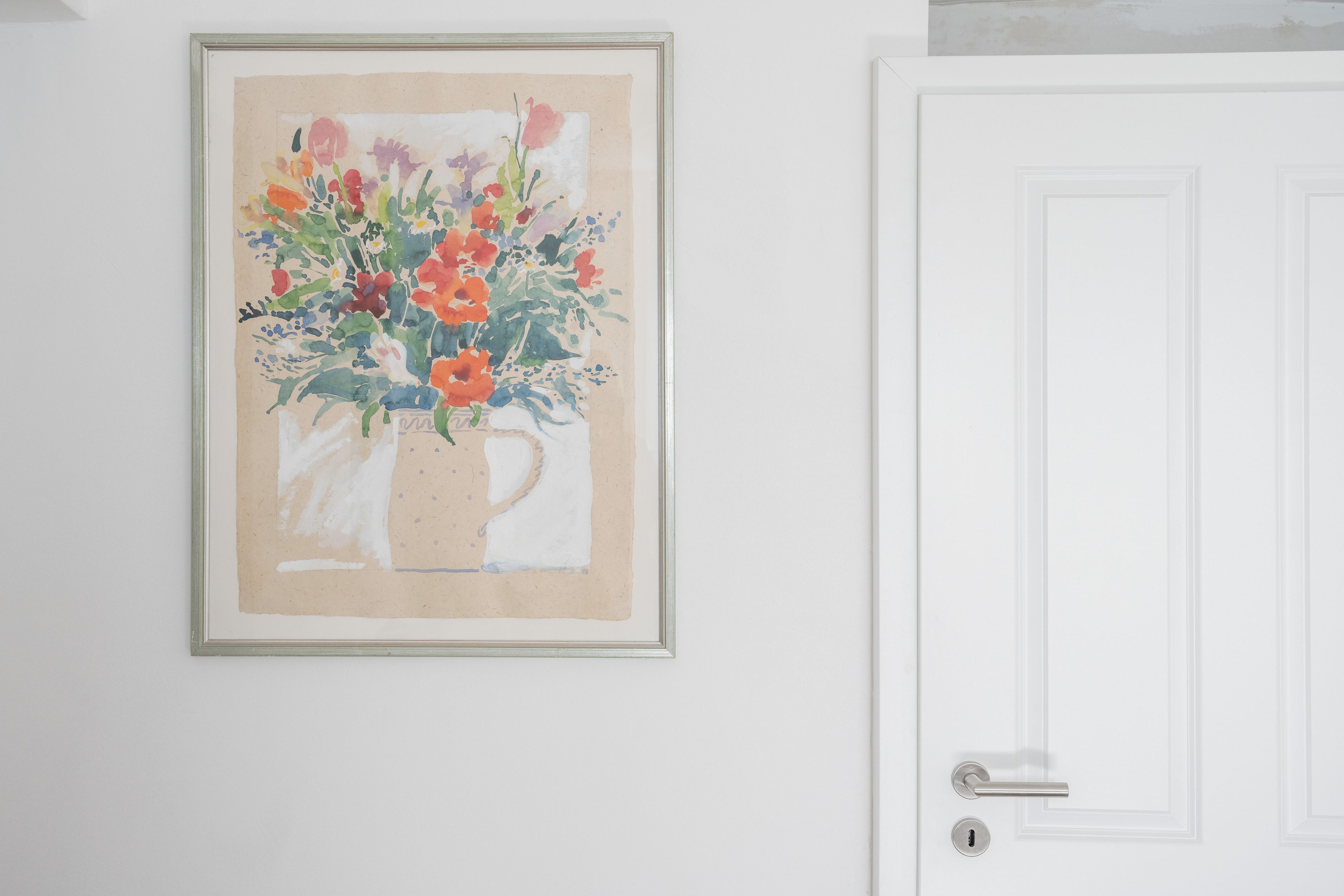 Un tableau à l’aquarelle représentant une composition florale, encadré et accroché au mur.