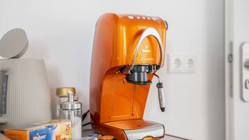 An orange coffee machine with a brand name, a box of tea, and a container of milk.