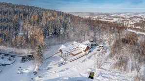 A large building with multiple wings, surrounded by snow-covered trees and a clear sky.