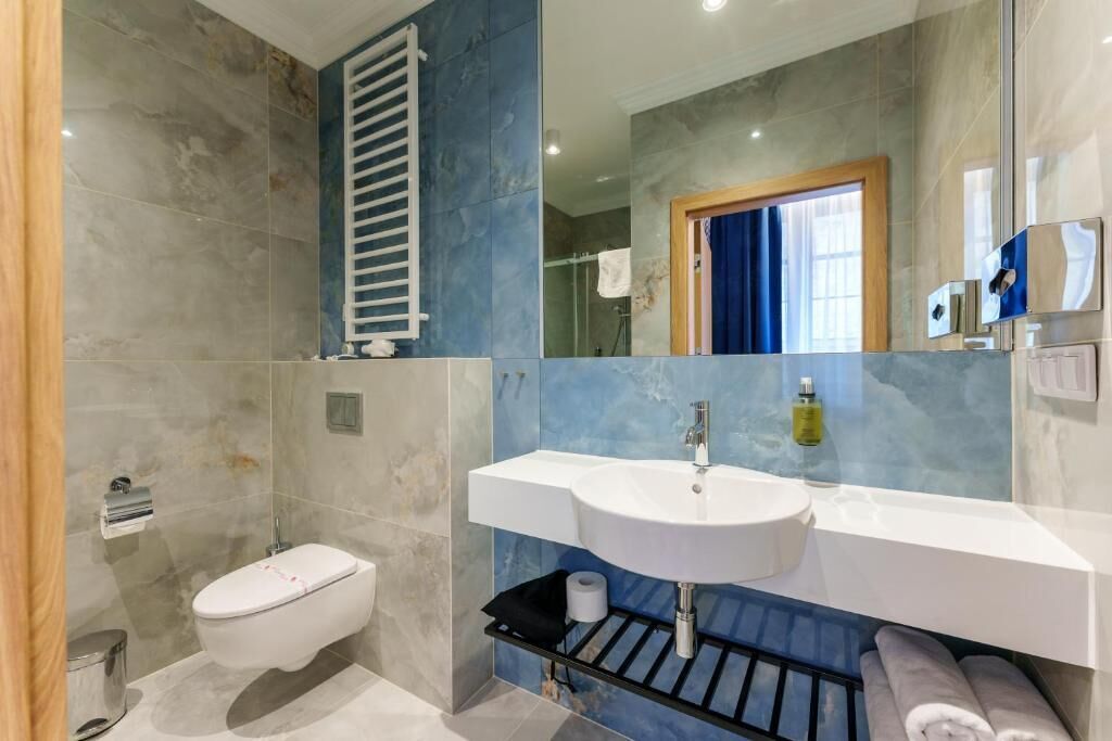 A modern bathroom with a white sink, a toilet, and a shower area.