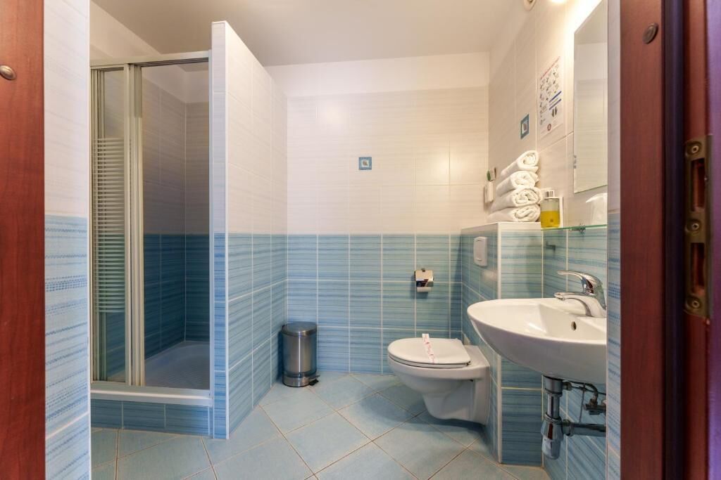 Ein Badezimmer mit Glasdusche, Toilette und Waschbecken mit Spiegel.