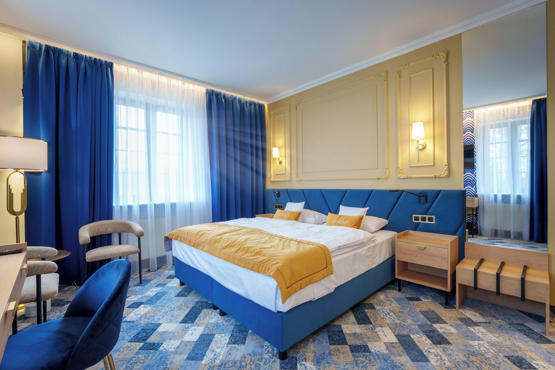 Una camera d'albergo con un letto grande, una scrivania, una sedia e uno specchio.