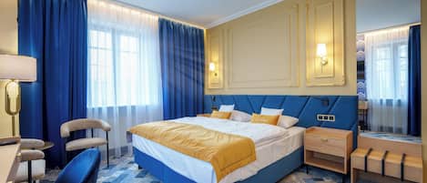 Una habitación de hotel con una cama grande, un escritorio, una silla y un espejo.