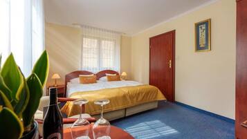 A hotel room with a bed, bedside table, and a window with curtains.