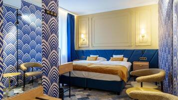 A hotel room with a large bed, a desk, and a chair.