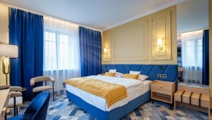 A hotel room with a large bed, a desk, and a chair.