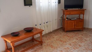 A room with a wooden table, a television on a wooden stand, and a patterned floor. - Holiday house Casa Argelio (Vallehermoso)