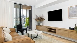 Ein modernes Wohnzimmer mit einer Couch, einem Couchtisch, einem Fernseher und einer Pflanze.