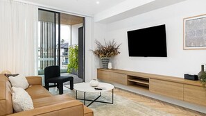 Ein modernes Wohnzimmer mit einer Couch, einem Couchtisch, einem Fernseher und einer Pflanze.