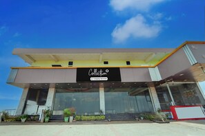 A modern building with a large entrance, a sign reading 'Collection Company-Serviced', and a clear blue sky above. - Super Collection O Madurai Theni Road (Usilampatti)