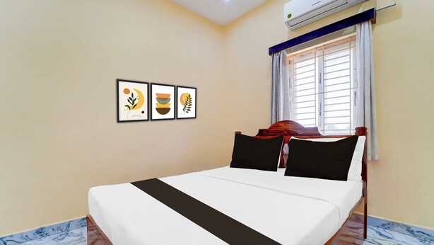 A hotel room with a bed, a window with curtains, and three framed artworks on the wall. - Super Collection O Madurai Theni Road (Usilampatti)