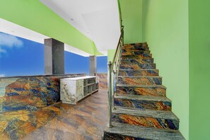 Una escalera con un diseño de mármol único, que conduce a un área de balcón con un banco de mármol y vistas al cielo.
