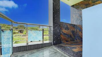 A modern bathroom with a glass partition, marble walls, and a view of the outdoors.