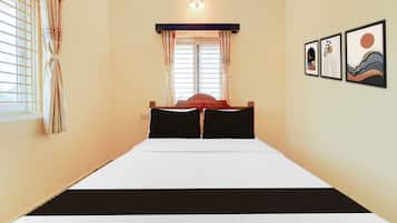 Una habitación de hotel con cama, cortinas, ventana y decoración en la pared.