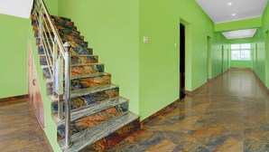 A hallway with a marble staircase and green walls. - Super Collection O Madurai Theni Road (Usilampatti)