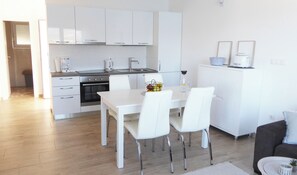 Eine moderne Küche mit weißen Schränken, einem Esstisch mit Stühlen und einem Kühlschrank.