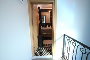 A hallway leading to a bathroom with a mirror, sink, and patterned floor.
