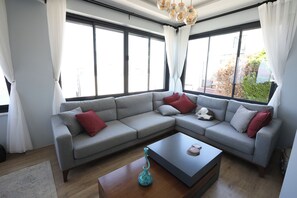 A modern living room with a grey sectional sofa, a wooden coffee table, and a vase.