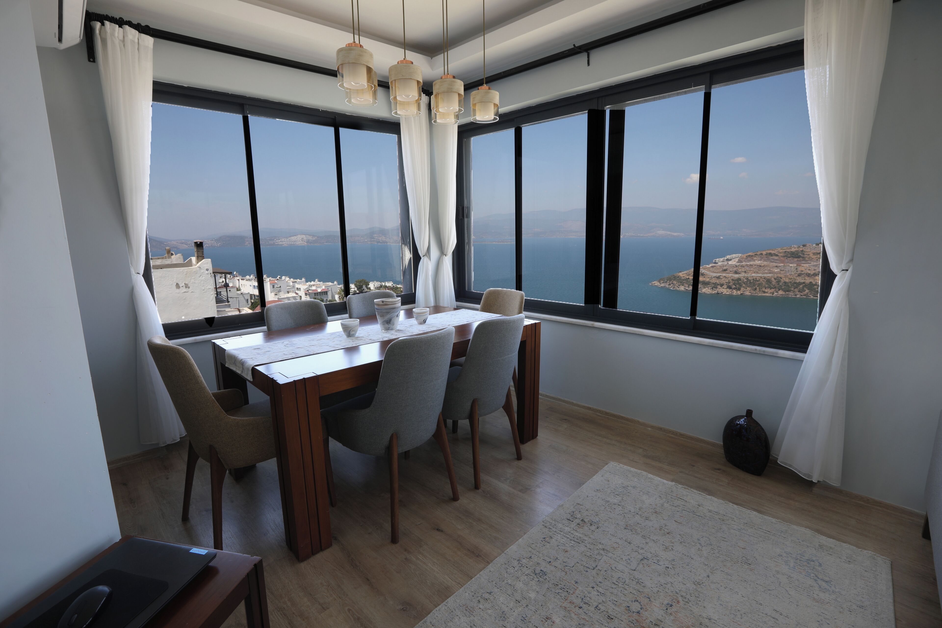 Een eetruimte met een tafel, stoelen en uitzicht op zee.