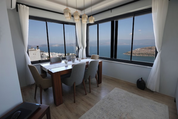 A dining area with a table, chairs, and a view of the sea.