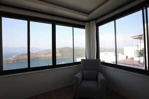 A room with a large window offering a view of a lake and hills.