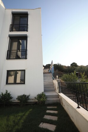 A white building with multiple windows and a staircase leading to a higher level.