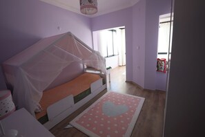 A child's bedroom with a bunk bed, a polka dot rug, and a window with curtains.