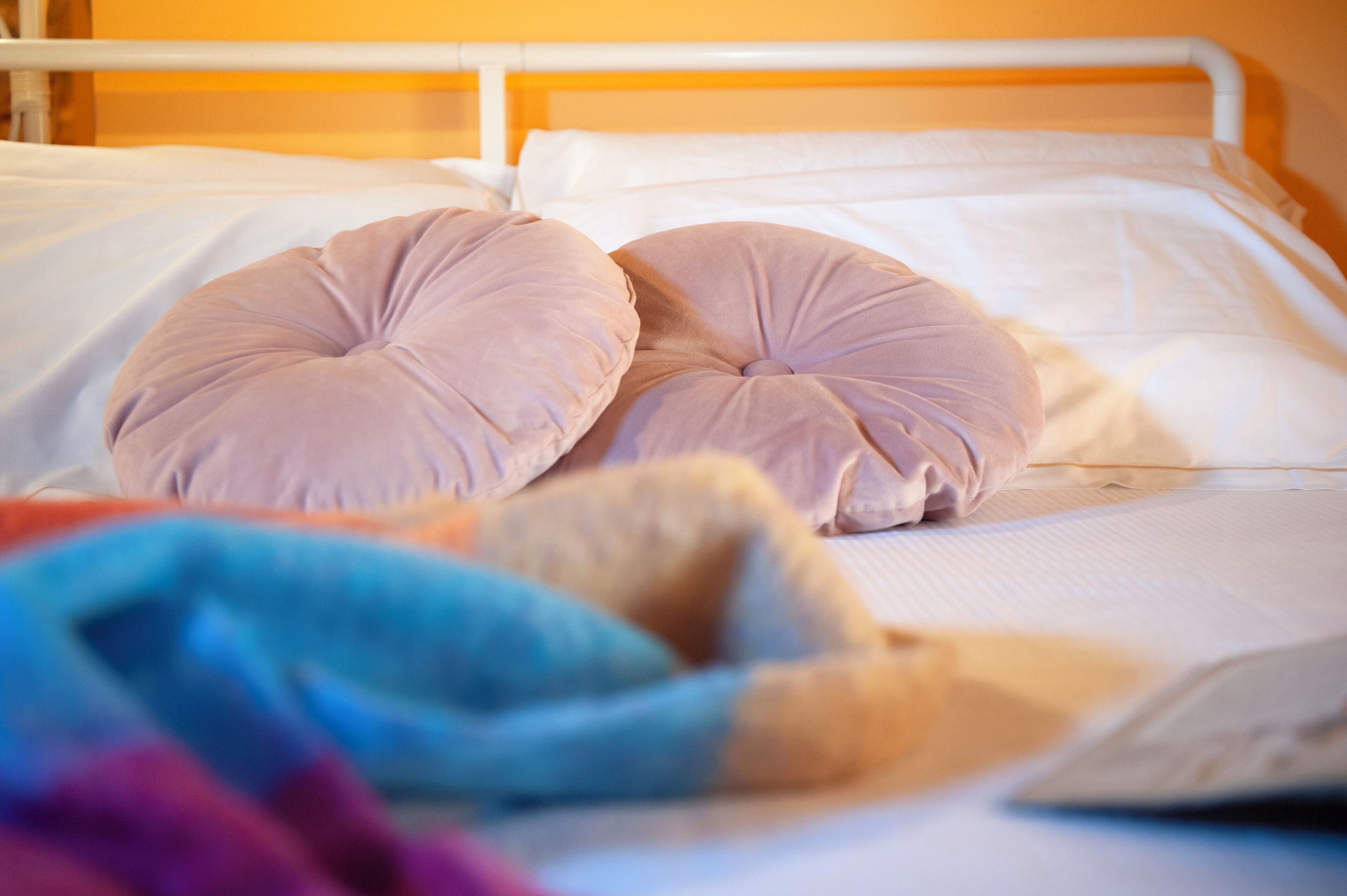 Una cama con dos almohadillas redondas y una manta.