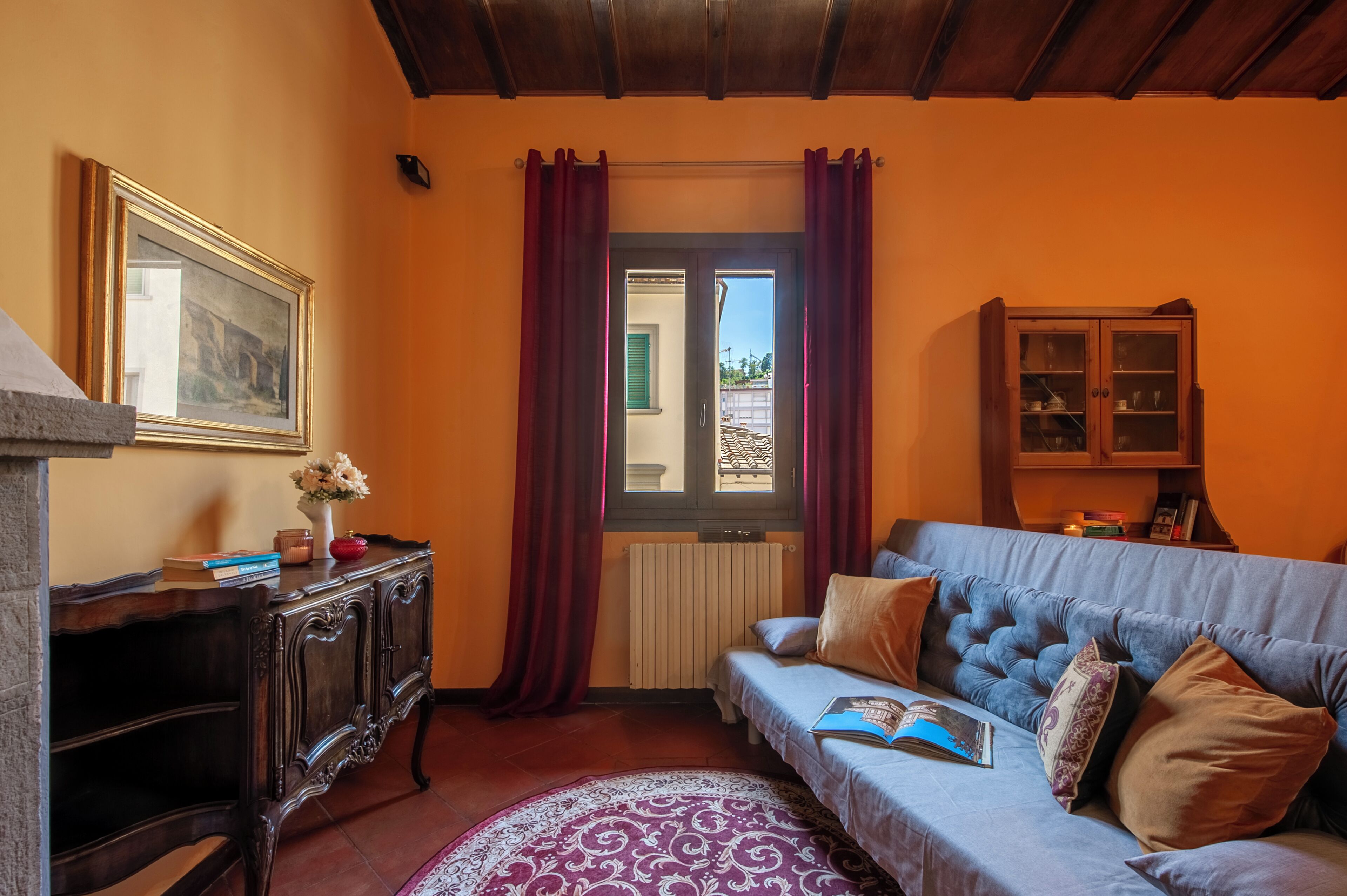 Una stanza con un armadio in legno, un divano, un quadro incorniciato e una finestra con tende.