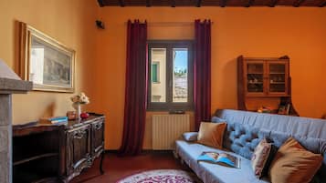 Una stanza con un armadio in legno, un divano, un quadro incorniciato e una finestra con tende.