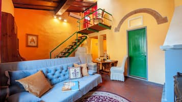 A cozy living room with a blue sofa, a green staircase, and a green door.