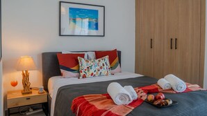 Ein Hotelzimmer mit einem Bett, einem Nachttisch, einer Lampe, einem gerahmten Bild an der Wand und einem Schrank.