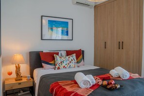 Ein Hotelzimmer mit einem Bett, einem Nachttisch, einer Lampe, einem gerahmten Bild an der Wand und einem Schrank.