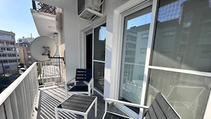 Ein Balkon mit Satellitenschüssel, zwei Stühlen und einem Tisch.