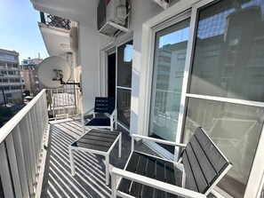 Ein Balkon mit Satellitenschüssel, zwei Stühlen und einem Tisch.