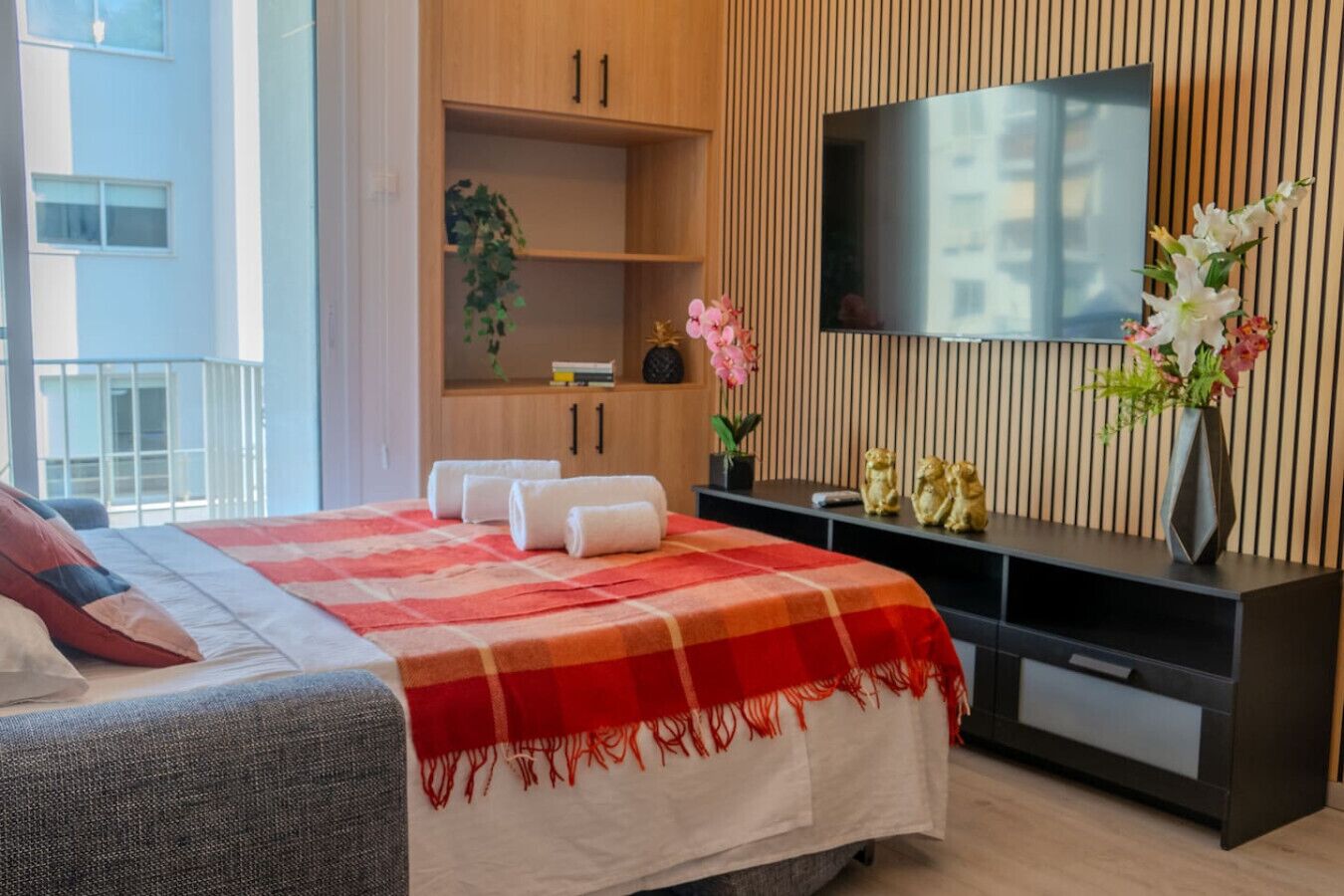Ein Hotelzimmer mit einem Bett, einem Fernseher, einem Schreibtisch und Blick ins Freie.