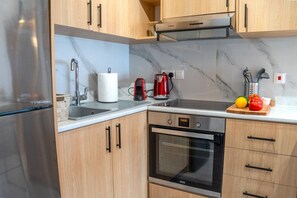 A kitchen with a stainless steel refrigerator, a built-in oven, wooden cabinets, a marble countertop, and a red kettle. - 4.97 Super Host`s New Boutique & Prime Location (Limassol)